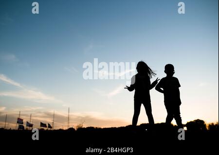 I bambini con silhouette in piedi con il segno di pace in Waco Texas Foto Stock