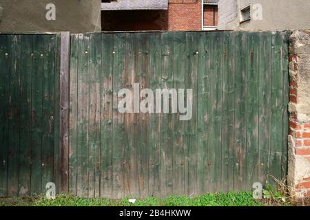 Un vecchio recinto in legno con vernice sbiadita e rusty cerniere. Foto Stock