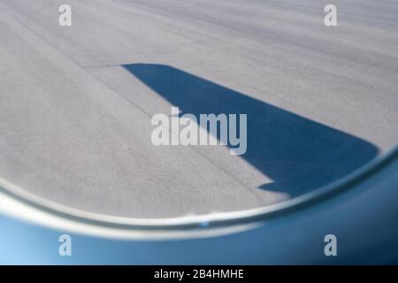 Vista dalla finestra dell'aereo sulla pista con l'ombra dell'ala Foto Stock