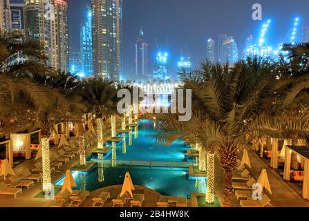 Giardino con piscina all'hotel Palace Downtown di notte nel centro di Dubai, nel Golfo Persico, negli Emirati Arabi Uniti Foto Stock