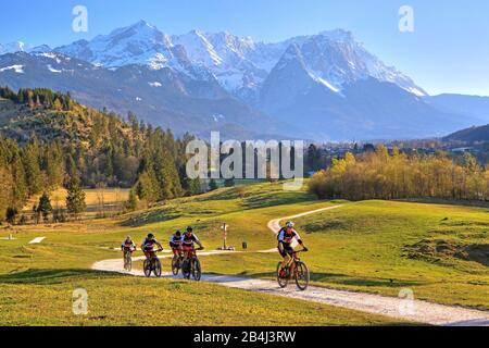 Ciclisti sulla Philosophenweg con Alpspitze 2628m Waxenstein 2277m e Zugspitze 2962m del Gruppo Zugspitze nelle montagne Wetterstein vicino Garmisch-Partenkirchen, Loisachtal, Werdenfelser Land, Zugspitzland, alta Baviera, Germania Foto Stock