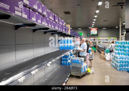 Il coronavirus in Australia conduce all'acquisto di massa di panic dei rotoli della toletta, l'uomo che compra alcuni dei pochi rotoli restanti della toletta in woolworths Foto Stock