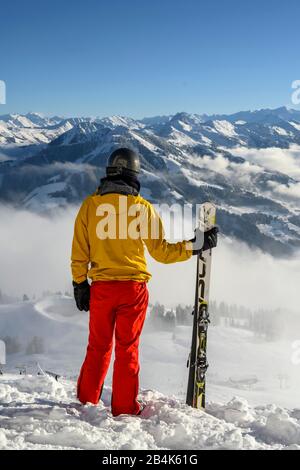 Sciatore in piedi sulla pista da sci, vista in lontananza, panorama montano innevato, cima Hohe Salve, SkiWelt Wilder Kaiser Brixenthal Foto Stock