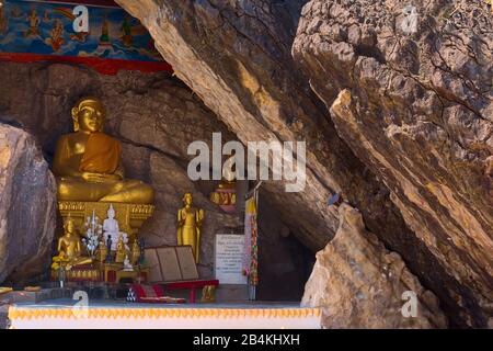 Statua dorata di Buddha su un crepaccio della roccia al Monte Phou si, a Luang Prabang, Laos. L'ingresso del santuario grotta si può vedere sulla destra Foto Stock