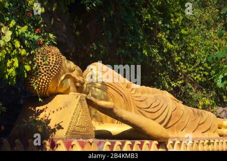 Statua dorata di Buddha reclinato sulla strada per la cima del Monte Phou si, una montagna sacra a Luang Prabang, Laos. Foto Stock