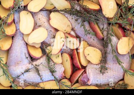 Cibo, preparazione, pollo nero, patate dimezzate, rosmarino, cena di Natale. Foto Stock