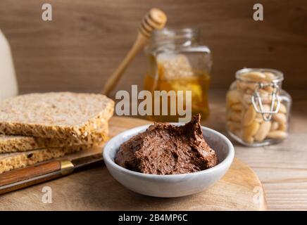 Cioccolato vegano fatto in casa sparso in una piccola ciotola fatta di burro di mandorle, cacao e miele. Foto Stock