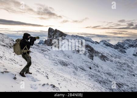 Fotografo naturale autoritratto nelle alte montagne del Karwendel all'inizio dell'inverno, con neve e vento con una grande macchina fotografica Foto Stock