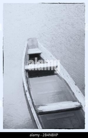Immagine fine in bianco e nero. Una barca di legno su un lago misty. Foto Stock