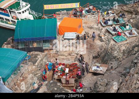 Busan, Corea del Sud - 18 marzo 2018: Le persone si trovano nel ristorante costiero di pesce all'aperto Haenyeochon sulle rocce costiere del parco naturale Taejongdae Foto Stock