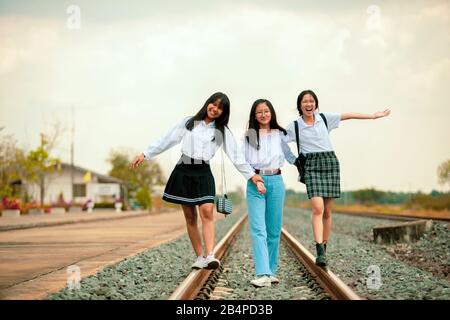 tre adolescenti asiatici che giocano con felicità sulla ferrovia Foto Stock