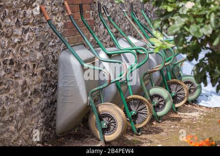 Fila di carriole appoggiati contro la parete di selce Foto Stock