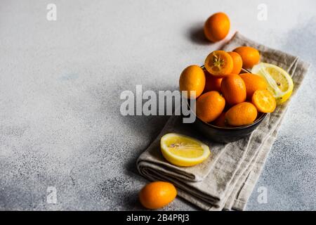 Concetto di cibo organico con frutta kumquat organge in una ciotola su sfondo di pietra con spazio di copia Foto Stock