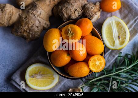 Concetto di cibo organico con frutta kumquat organge in una ciotola su sfondo di pietra con spazio di copia Foto Stock