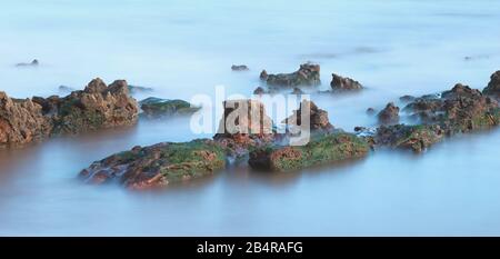 Rocce sulla spiaggia vicino alla città di Sidmouth presa con lunga esposizione Foto Stock