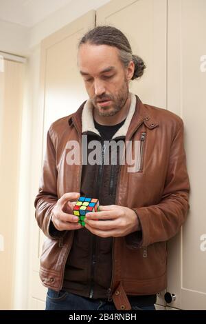 Un uomo che gioca con un cubo Rubix Foto Stock