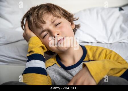 Bambino con mal di testa, ragazzo di 9 anni, con dolore viso distorto, immagine simbolica, Foto Stock