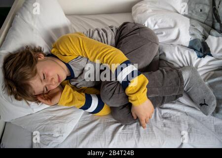 Bambino con mal di testa, ragazzo di 9 anni, con dolore viso distorto, immagine simbolica, Foto Stock