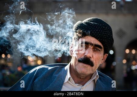 Iraq, Kurdistan Iracheno, Arbil, Erbil. Ritratto di un uomo curdo iracheno sul parco Shar. Il fumo dalla sua sigaretta esce dalla bocca. È stanco Foto Stock