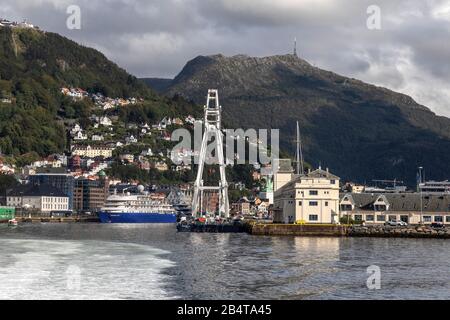 Gru nave Tronds Ascensore 8 a Tollboden banchina, nel porto di Bergen, Norvegia. In background, nave da crociera Hebridean Sky. Monte Floeyen E Monte Ulriken Foto Stock