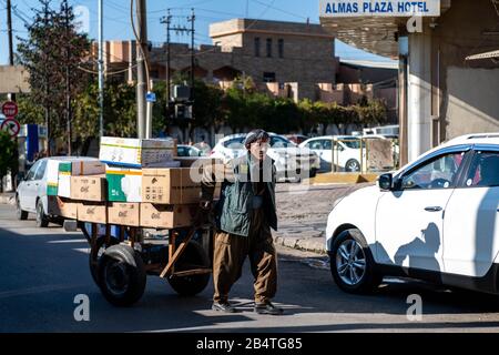 Uomo curdo che tira un carrello completamente carico attraverso la pioggia Foto Stock