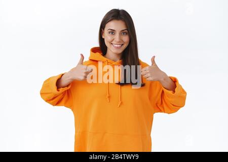 Continua a andare, sei il migliore. Incoraggiante e solidale donna bruna affascinante con il sorriso beaming, mostrando pollici-in su in approvazione, come o accettare Foto Stock