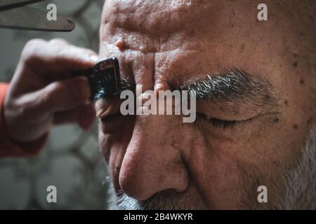 Uomo di 80 anni molto vecchio ottenere Il Suo sopracciglio Tagliato in bagno Foto Stock