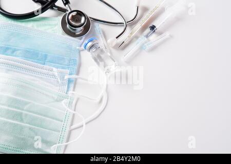 Stetoscopio con maschera facciale protettiva per iniezione o maschera medica su sfondo bianco. Proteggere Coronavirus. Foto Stock