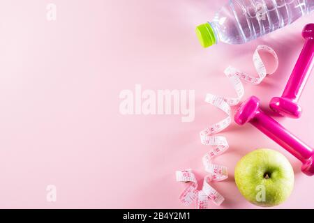 Uno stile di vita sano, cibo e sport concept. Vista superiore dell'atleta Peso attrezzatura di misurazione in scala il nastro rosa dumbbell, sport bottiglie di acqua, frutta e v Foto Stock