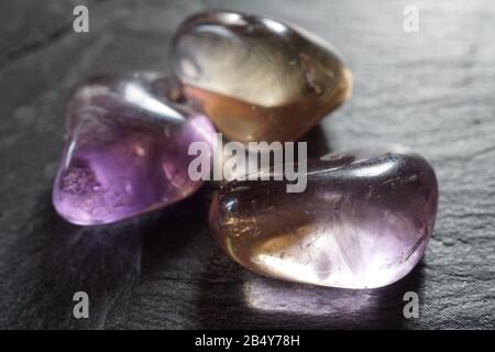 Gruppo di ciottoli ametrini tumbled su sfondo grigio ardesia Foto Stock