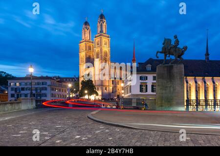 Il famoso Grossmunster churche lungo il fiume Limmat di notte nel centro storico di Zurigo, la città più grande della Svizzera Foto Stock