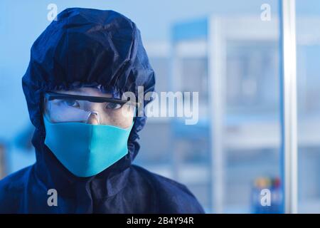 Orizzontale primo piano ritratto di giovane non riconoscibile indossando tuta protettiva da laboratorio, occhiali e maschera, copia spazio Foto Stock