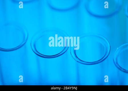 Angolo alto orizzontale primo piano di provette in vetro trasparente vuote in luce blu Foto Stock