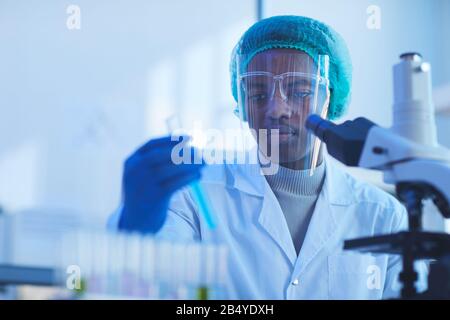 Orizzontale torace su ritratto di giovane scienziato medico maschile indossando maschera protettiva facendo test di laboratorio, copia spazio Foto Stock