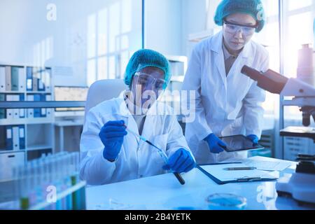 Ritratto orizzontale di due giovani scienziati che indossano coworking protettivo uniforme in moderno laboratorio medico, copia spazio Foto Stock