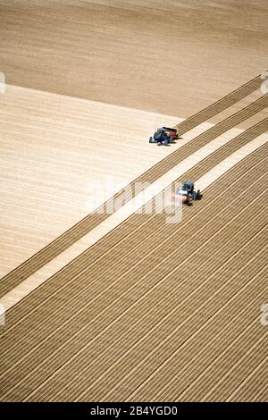 Una vista aerea di due trattori che lavorano nel campo piantando. Un'ottima immagine di sfondo con molta area per la copia. Foto Stock
