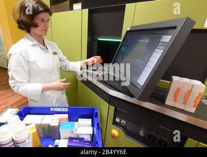 Lipsia, Germania. 06th Mar, 2020. Un farmacista nella farmacia delle rose nella foresta di Auwald utilizza un computer per riempire il negozio di medicina dove un robot sta lavorando. Quando richiesto da un computer, il robot recupera i medicinali e gli altri farmaci necessari dai compartimenti alti e li trasporta attraverso un sistema di trasporto al dispensario nella sala di vendita. Credito: Waltraud Grubitzsch/Dpa/Alamy Live News Foto Stock