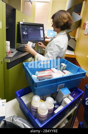 Lipsia, Germania. 06th Mar, 2020. Un farmacista nella farmacia delle rose nella foresta di Auwald utilizza un computer per riempire il negozio di medicina dove un robot sta lavorando. Quando richiesto da un computer, il robot recupera i medicinali e gli altri farmaci necessari dai compartimenti alti e li trasporta attraverso un sistema di trasporto al dispensario nella sala di vendita. Credito: Waltraud Grubitzsch/Dpa/Alamy Live News Foto Stock