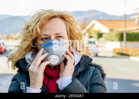 La donna bianca cammina la strada con la maschera protettiva nei tempi del coronavirus 'Covid - 19' che colpisce molte persone Foto Stock