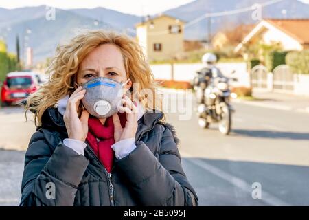 La donna bianca cammina la strada con la maschera protettiva nei tempi del coronavirus 'Covid - 19' che colpisce molte persone Foto Stock