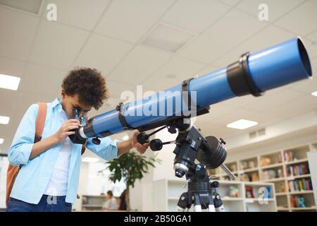 Orizzontale medio basso angolo di scuola media guardando inizia attraverso moderno telescopio, copia spazio Foto Stock