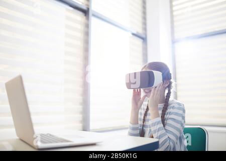 Ritratto orizzontale medio di una ragazza caucasica di undici anni irriconoscibile usando visore VR sorridente, spazio di copia Foto Stock