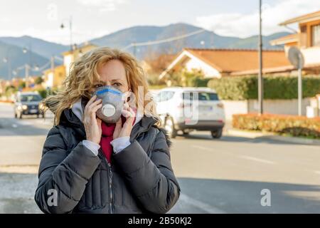 La donna bianca cammina la strada con la maschera protettiva nei tempi del coronavirus 'Covid - 19' che colpisce molte persone Foto Stock