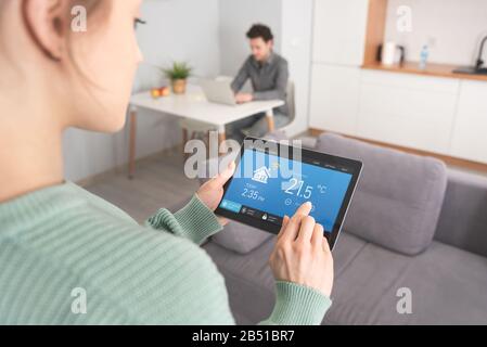 Donna che utilizza un'applicazione smart home su tablet. Concetto di sistema smart home Foto Stock