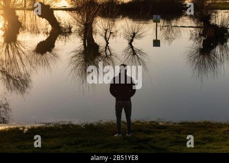 Un giovane osserva l'inondazione del fiume Cherwell che rende un pub giardino a Oxford inaccessibile dopo la pioggia intensa Foto Stock