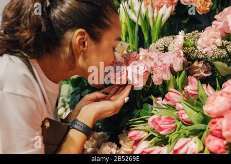 Primo piano di una donna che odorava i fiori nel negozio di fiori. Foto Stock