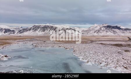 Veduta aerea del lago ghiacciato con montagne innevate sullo sfondo Foto Stock
