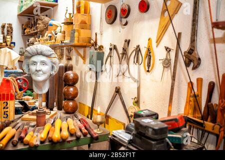 busto in gesso in laboratorio artistico con una varietà di utensili e scalpelli appesi a parete Foto Stock