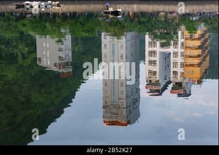 Isola Di Cat Ba, Vietnam, 17 Ottobre 2019. Bellissimo lago, edifici di riflessione in acqua. Pescatore su una barca di pesca Foto Stock