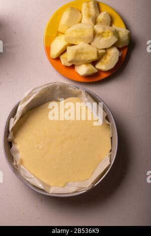 Donna che versa l'impasto per una torta in uno stampo di alluminio imbottito con carta pergamena. Foto Stock
